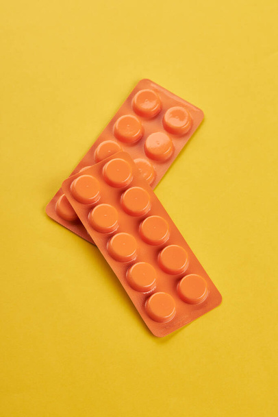 egészségügyi wellness koncepció. narancs tabletták sárga háttérrel. Másolás. minimális - Fotó, kép