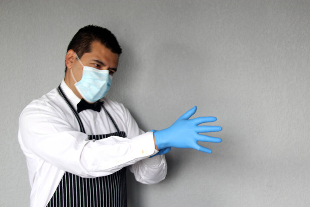Latino waiter man with protective mask, works with latex gloves, new normal in restaurants. covid-19 - Foto, imagen