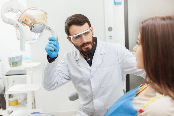 Dentista masculino maduro barbudo examinando los dientes de una paciente femenina. Cuidado dental, concepto de odontología de seguros - Foto, Imagen