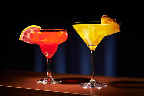 Two fruit cocktails on a bar counter on a dark blue background. - Фото, изображение
