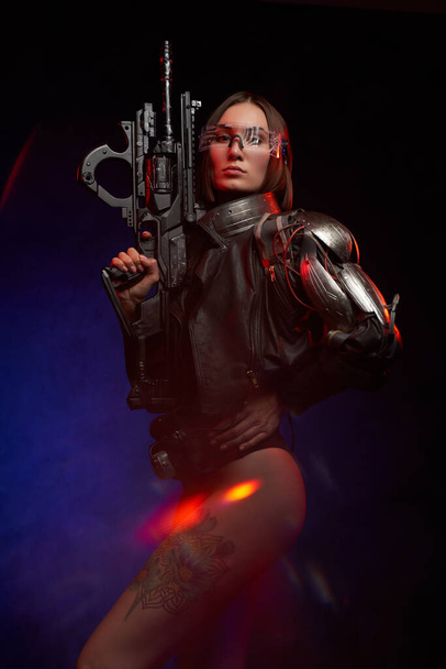 Verführerische und martialische Frau posiert mit Gewehr und blickt in die Kamera - Foto, Bild