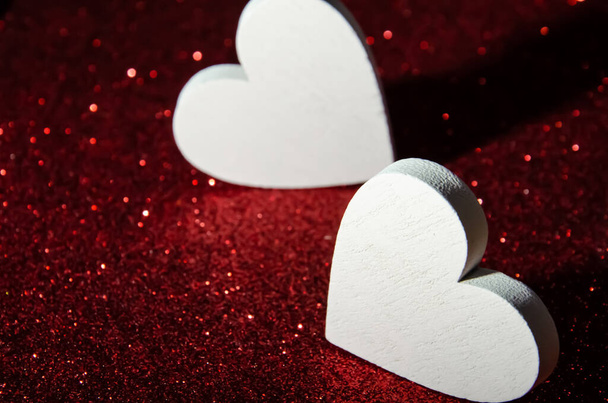 Valentines day abstract background. Shiny sparkle red metallic glitter texture. White decorative Hearts on gules shiny background with copy space. Selective focus. Background for greeting card. - Photo, Image