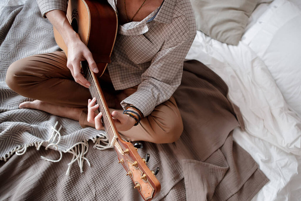 Man playing acoustic guitar at home on bed cozy - Photo, image