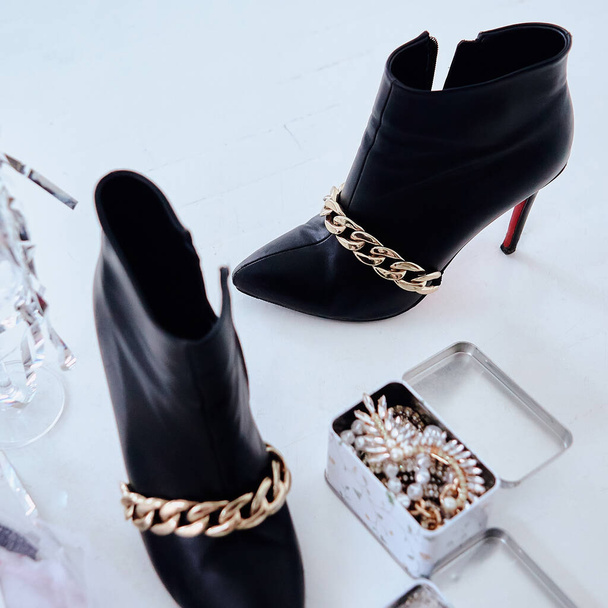 Chaussures en cuir pour femmes bottes de cheville noires avec chaîne en or tendance de la mode - Photo, image
