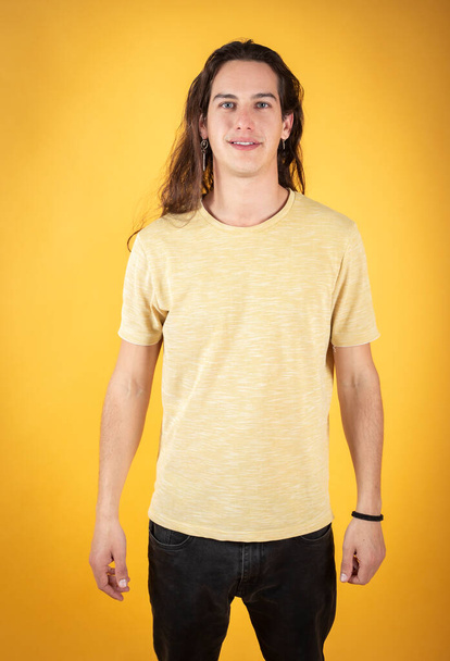 attractive handsome man with long hair blue eyes in yellow shirt,head-on on yellow background - Valokuva, kuva