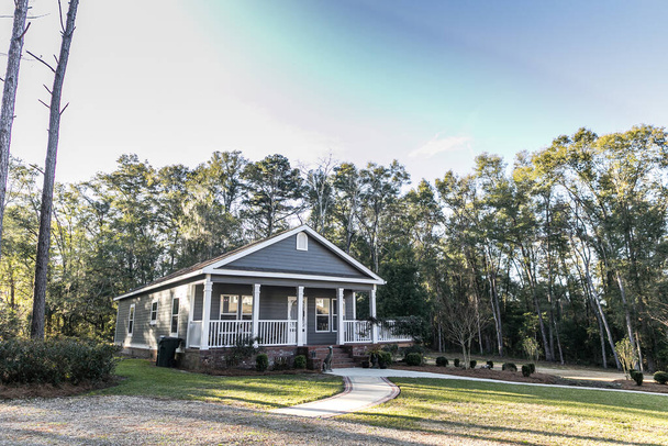 Pequeña casa móvil gris azul con un porche frontal y lateral con barandilla blanca. - Foto, Imagen