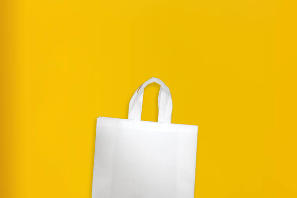 美しい不織布食料品ショッピングバッグ付き黄色の背景。トートエコバッグ - 写真・画像