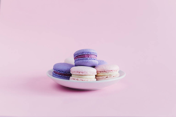 Tasty french macarons on a pink pastel background. Pink and violet macarons. Place for text. - Foto, Bild