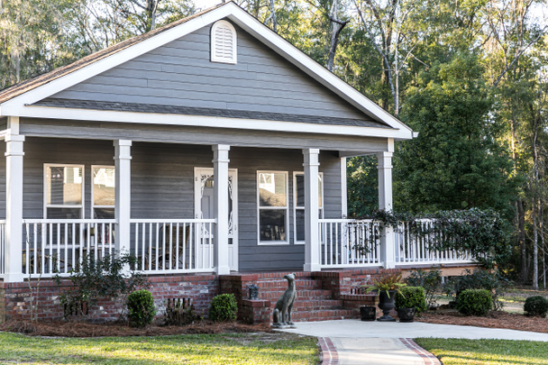 Primer plano de la pequeña casa móvil gris azul con un porche frontal y lateral con barandilla blanca - Foto, imagen