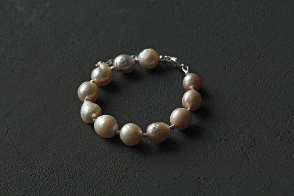 Bracelet made of natural Kasumi pearls and 925 sterling silver. Handmade jewelry. Handmade bracelets on a black modern background. - Photo, Image