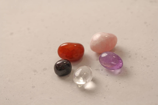 Egy sor természetes kövek fekszik egy világos fehér háttér, gránát, ametiszt, carnelian, rock kristály és rózsa kvarc. Természetes kövek, ásványi és féldrágakövek gyűjtése. - Fotó, kép