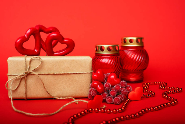 Gift in craft paper, red hearts with red candlesticks on a red background - Fotografie, Obrázek