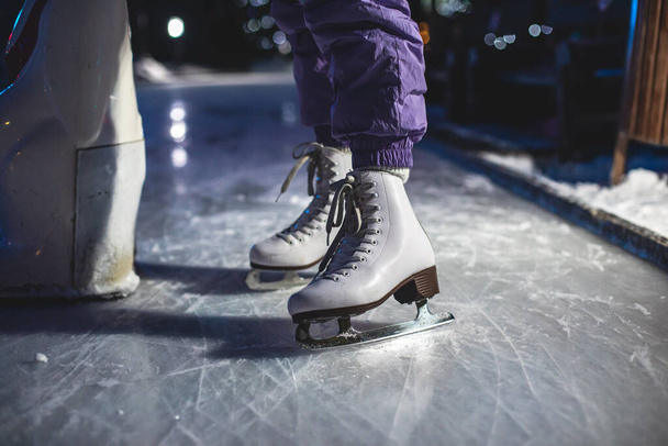 Close up view of new white ice skates boots on rink in motion, girl ice skating on the arena, concept of ice skating in winter, holiday christmas xmas time - Photo, Image
