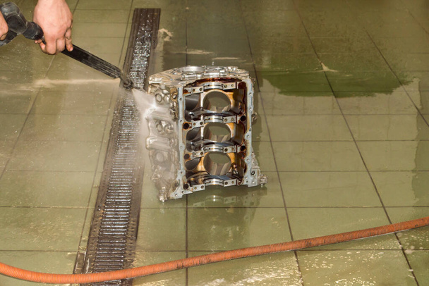 Мойка блока цилиндров двигателя струей воды под давлением со стороны стирального пистолета в автомойке - Фото, изображение