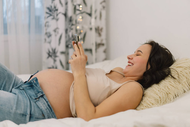 Happy viehättävä raskaana oleva nainen käyttää matkapuhelinta. Raskaana oleva nainen. - Valokuva, kuva