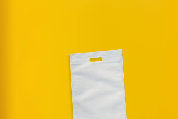 Hermosa bolsa de compras no tejida con fondo amarillo. Bolsas de mano ECO - Foto, Imagen