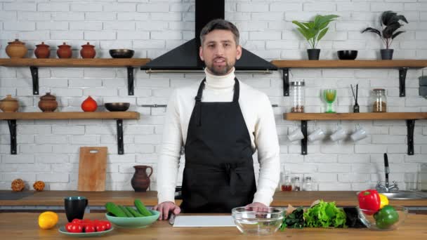 Man σεφ στην ποδιά διδάσκει νοικοκυρά online βίντεο μαγειρικής webinar στην κουζίνα - Πλάνα, βίντεο