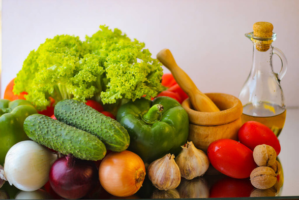 Подготовка к замечательному вегетарианскому ужину. Болгарский перец, зеленые огурцы, лук, чеснок, листья салата и бутылка оливкового масла - Фото, изображение
