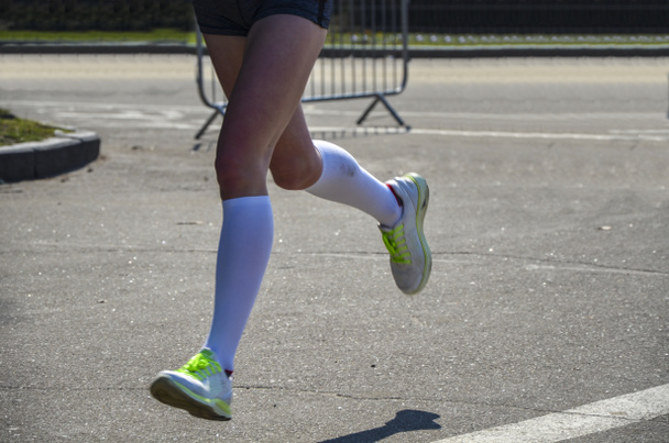 市内マラソン圧縮ソックスを実行している若い女性ランナーの足 - 写真・画像