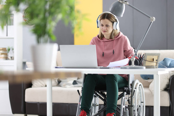 Nuori nainen pyörätuolissa työskentelee kannettavan tietokoneen kotona - Valokuva, kuva