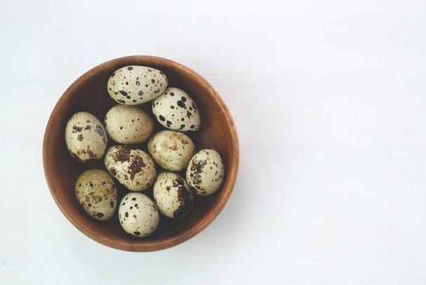 Quail eggs in a wooden plate on a white background. Natural organic farm product - Foto, Imagen