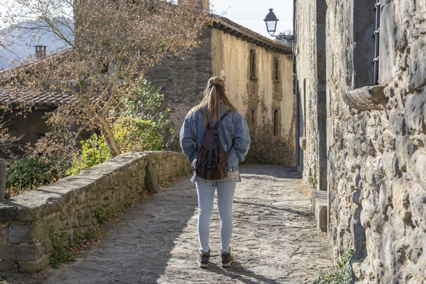 Back view of beautiful tourist woman walking in old medieval town of Rupit in Barcelona, Spain.Traveling lifestyle concept. - Fotó, kép