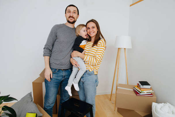 Family moved into a new home, image against a backdrop of boxes and white walls - Valokuva, kuva