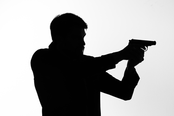 σκιά ενός άνδρα με ένα όπλο στα χέρια του στοχεύοντας ντετέκτιβ έγκλημα φως φόντο - Φωτογραφία, εικόνα
