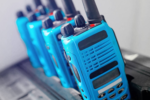 Un ensemble de talkies-walkies bleus se tiennent dans une rangée. Un dispositif pour transmettre une communication radio stable sur une distance. - Photo, image