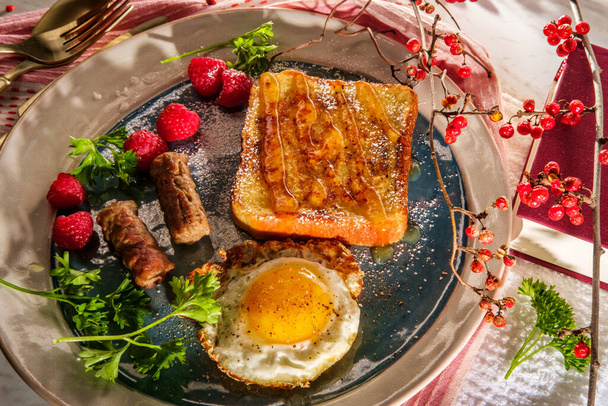 Классический американский завтрак Французский тост с кленовым сиропом подается с гарниром из колбасных колец и жареным яйцом солнечная сторона вверх - Фото, изображение
