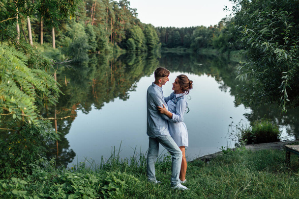 Young couple is hugging and walking near the lake on sunny day. Man and woman on summer holiday. Concept of lovely family. selective focus. - Photo, Image