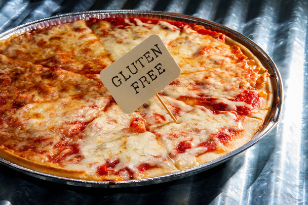 Tarte à pizza sans gluten de style New York servie sur une boîte de cuisson jetable avec fond de panneau métallique nervuré - Photo, image