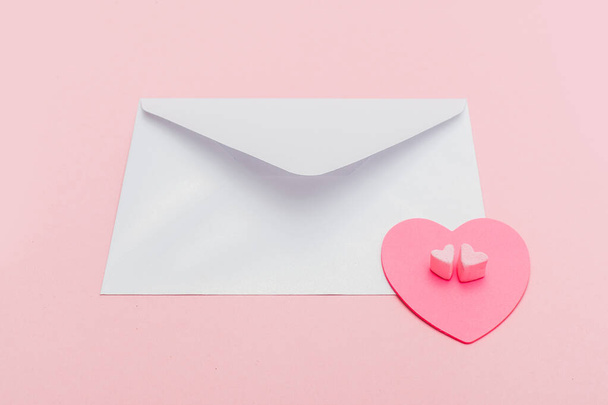 closed pearlescente envelope with paper heart on the pink background - Foto, imagen