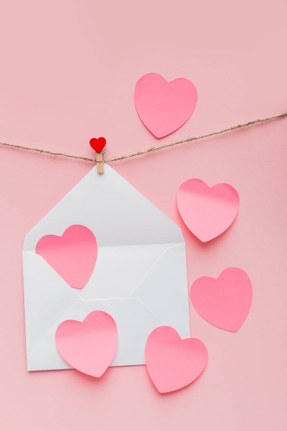 open mother-of-pearl envelope hanging on a rope on clothespins with red hearts - Foto, Imagem