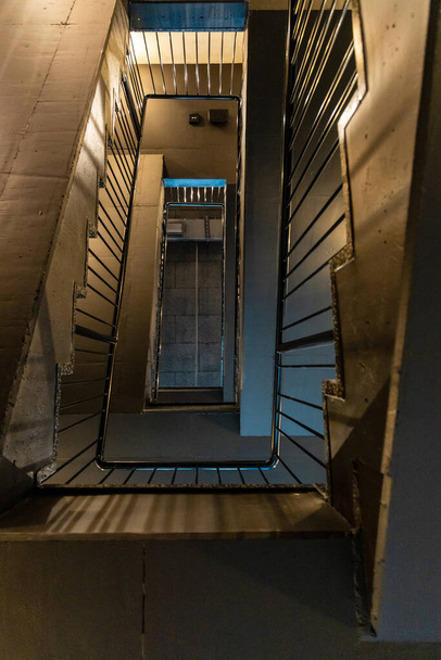 Ανάποδη όψη σε ορθογώνια σπειροειδή σκάλα με μαύρα μεταλλικά κάγκελα - Φωτογραφία, εικόνα