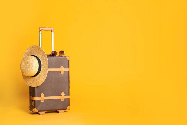 Vintage travel suitcase with hat and sunglasses on yellow background, space for text. Summer vacation - Fotografie, Obrázek