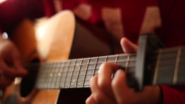 Un uomo con un maglione rosso suona una chitarra acustica all'interno, una visione ravvicinata di un'ampia apertura aperta - Filmati, video