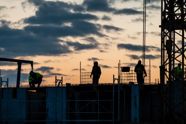 Σκιές των εργαζομένων στις κατασκευές σε ένα εργοτάξιο στο afterglow - Φωτογραφία, εικόνα