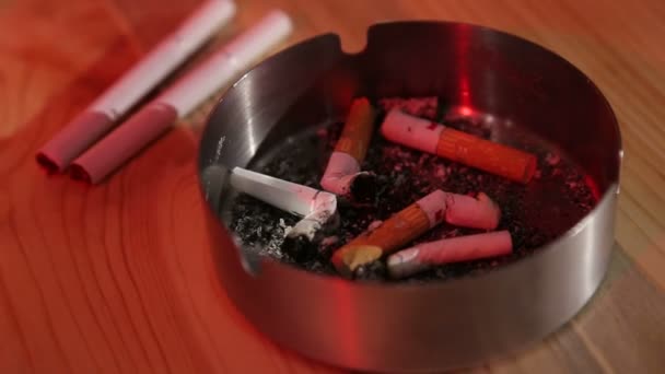 Ein Mann in einer Bar steckt eine Zigarette in einen Aschenbecher und nimmt eine neue Zigarette - Filmmaterial, Video