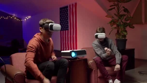 Młodzi mężczyźni w słuchawkach grający razem w wirtualną grę wideo - Materiał filmowy, wideo