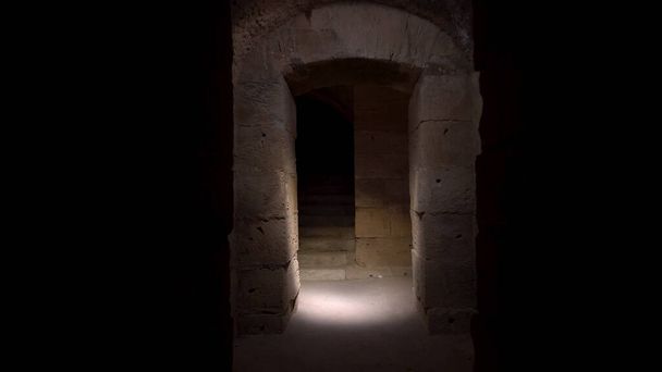 Pasar por un largo y oscuro sótano romano. Sótano bajo el anfiteatro en El Jem, Túnez. Antiguo edificio romano. La cámara se acerca.
 - Foto, Imagen