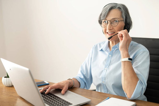 Senior female operator answering to the customer - Foto, afbeelding