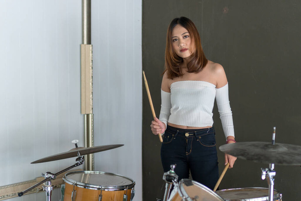 Beautiful young woman smiling while playing the drums. Concept music - Photo, Image