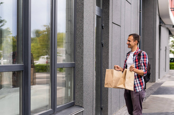 dodávka, pošta a lidé koncept - šťastný muž doručující jídlo v jednorázovém papírovém sáčku k zákazníkovi domů - Fotografie, Obrázek