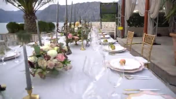 Стол на свадебном банкете, украшенный цветами, подсвечниками и молодыми гранатами на пирсе в Которском заливе - Кадры, видео