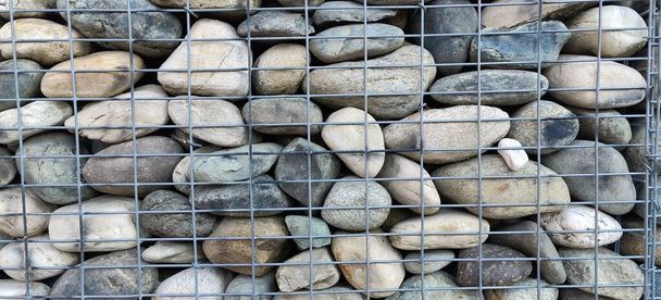 金属製の檻の中の川の石の壁。高品質の写真 - 写真・画像