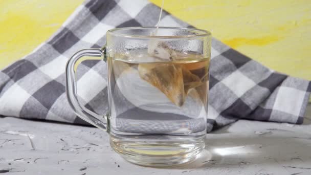 Ponga la bolsa de té en un tazón de vidrio de agua caliente de cerca. Hacer delicioso té de hierbas. - Imágenes, Vídeo