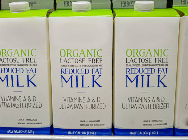 Pół galonowe kartony laktozy pozbawione tłuszczu mleko organiczne na półce lodówki. Dotyczy to osób z nietolerancją laktozy z powodu niedoboru enzymatycznego laktazy u dorosłych.. - Zdjęcie, obraz