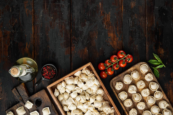 Tortellini aux raviolis italiens crus au parmesan et basilic frais, tomates posées sur un vieux fond de table en bois foncé, vue de dessus à plat, avec copyspace et espace pour le texte - Photo, image
