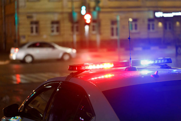νύχτα φώτα αυτοκινήτων της αστυνομίας στο δρόμο της πόλης με πολιτικό αυτοκίνητο σε θολή φόντο - Φωτογραφία, εικόνα